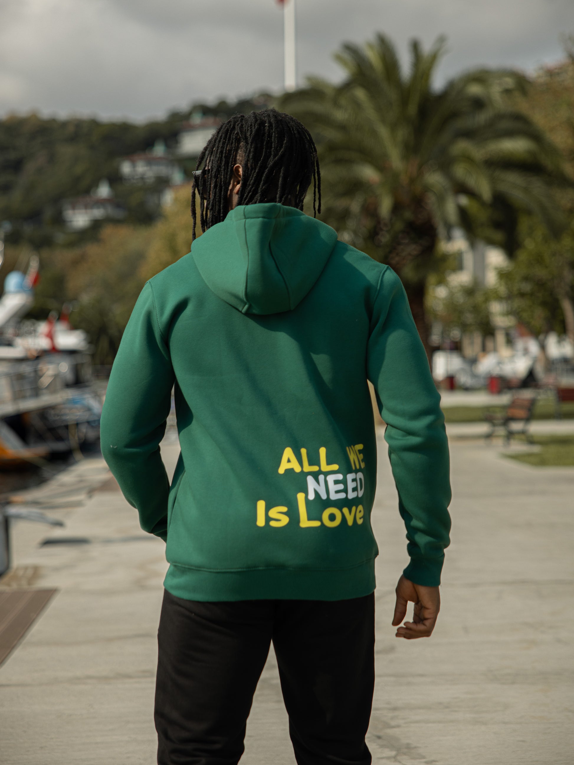 Sudadera con capucha, bolsillos y cremallera de algodón y poliéster con diseño "All We Need Is Love" en color verde. Ideal para un look casual y cómodo.